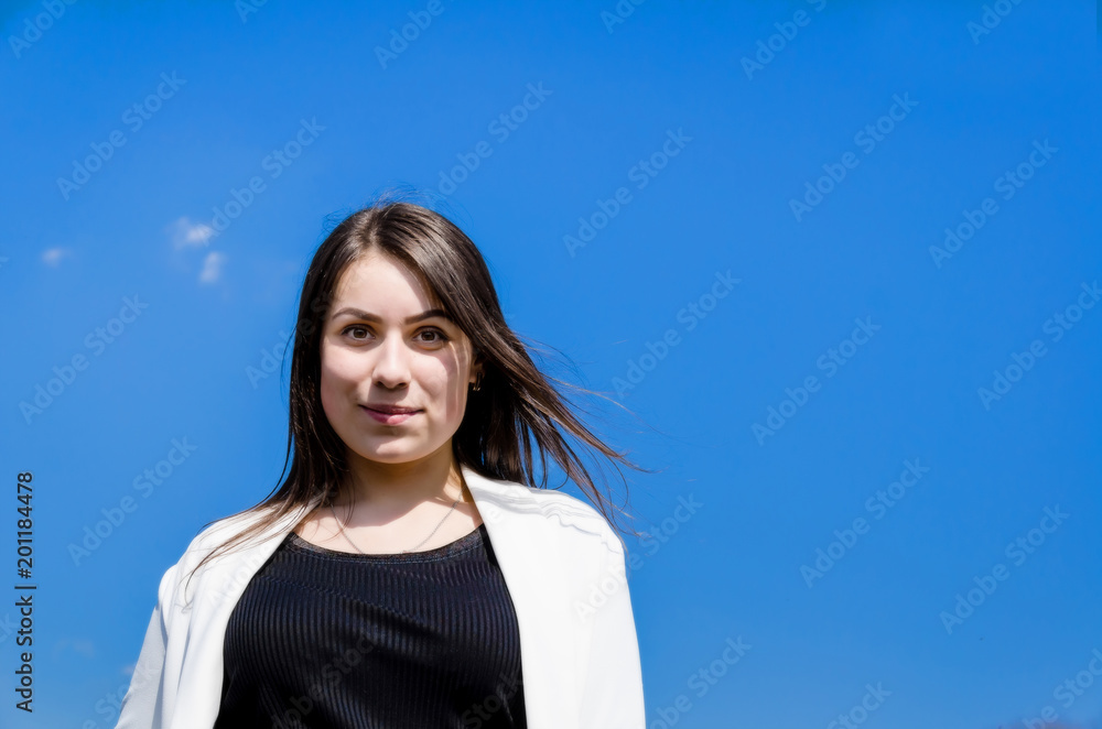 Portrait of a beautiful young brunette girl on a blue sky background. Portrait of a beautiful young brunette girl on a blue sky background.