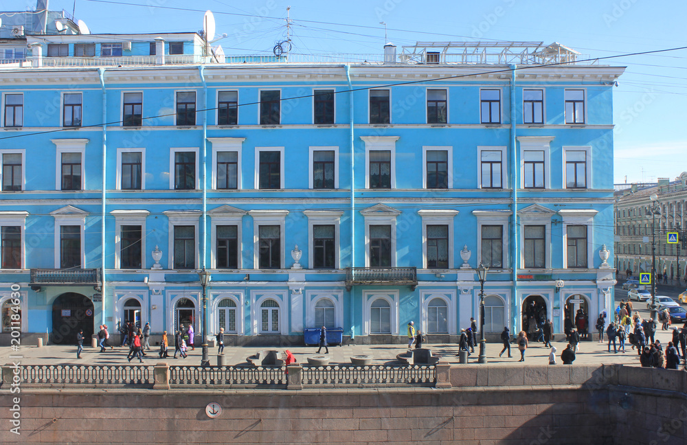 Classical Blue Architecture Building Facade in Downtown St. Petersburg, Russia. Exterior Detail of Old Multi-Storey Colorful Building with Alley and People Walking in Front on Sunny Day Background.