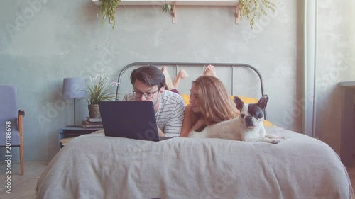 Happy young couple with french dog with laptop at home. Slow motion photo