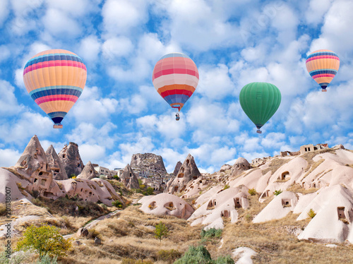 Uchhisar Fortress and colorful hot air balloons flying over Pigeon Valley in Cappadocia, Turkey