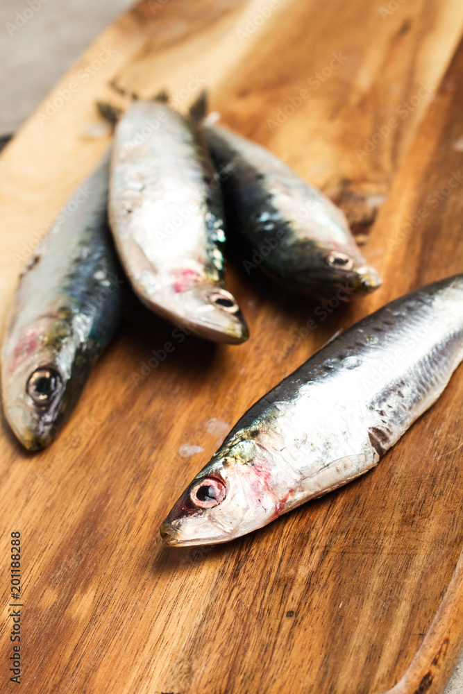 Sardinas sobre frescas y crudas sobre una tabla de madera rústica. Vista superior y de cerca Sardinas sobre frescas y crudas sobre una tabla de madera rústica. Vista superior y de cerca