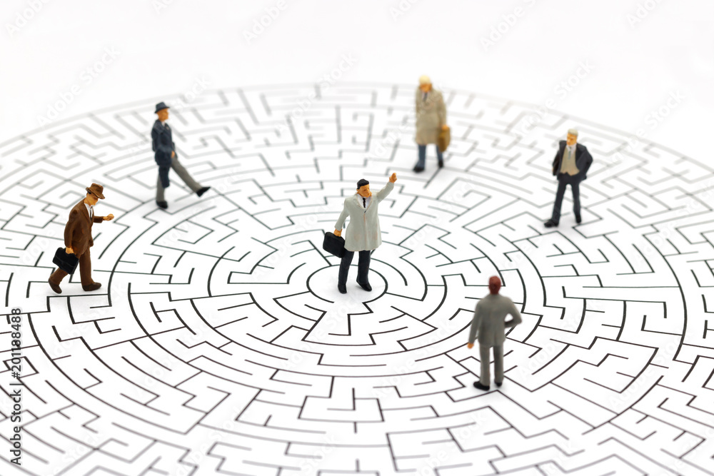 Miniature people: Businessman standing on center of maze. Concepts of finding a solution, problem solving and challenge. Miniature people: Businessman standing on center of maze. Concepts of finding a solution, problem solving and challenge.