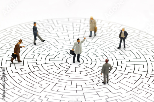 Miniature people: Businessman standing on center of maze. Concepts of finding a solution, problem solving and challenge.