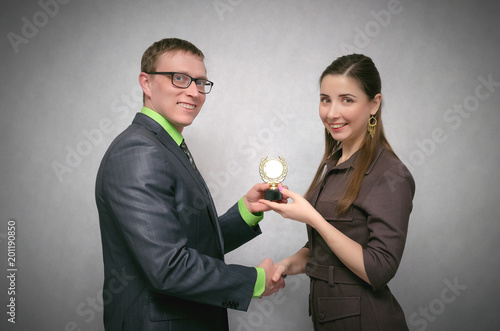 Fotografie Rewarding a person with a gold medal for first place and victory at competitions or business success isolated on gray background