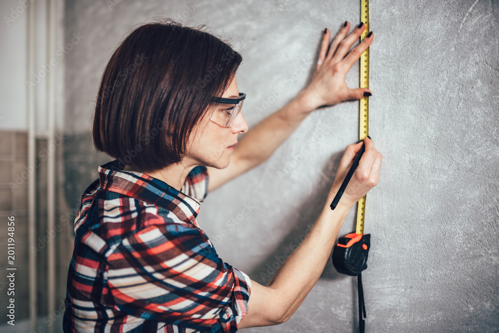 Woman measuring wall in kitchen
