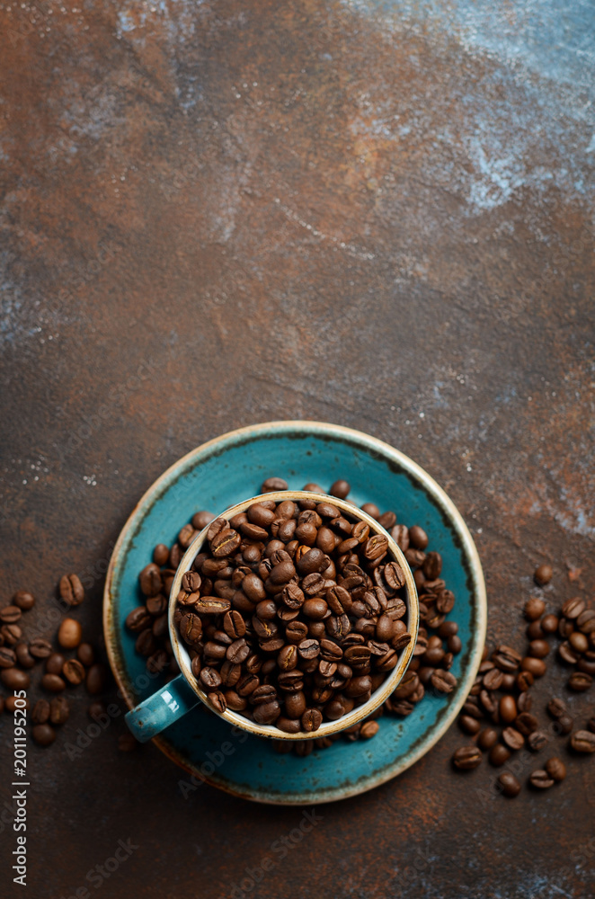 Natural organic roasted coffee beans in blue cup on dark rusty background, top view, flat lay, copy space. Natural organic roasted coffee beans in blue cup on dark rusty background, top view, flat lay, copy space.