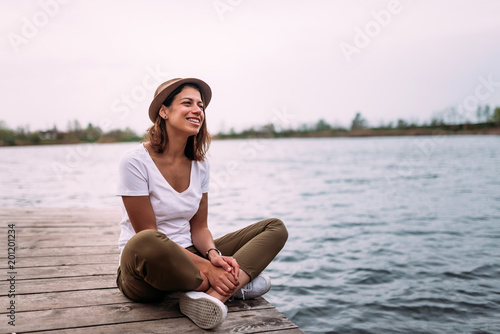 Young woman relaxes on the edge of a wooden jetty.