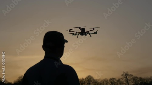 Man silhouette drone control at sunset