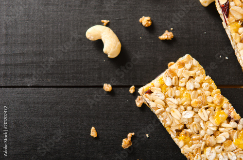 Muesli bar with nuts, berries and oat flakes on black wooden table. Healthy food, breakfast. Top view. photo