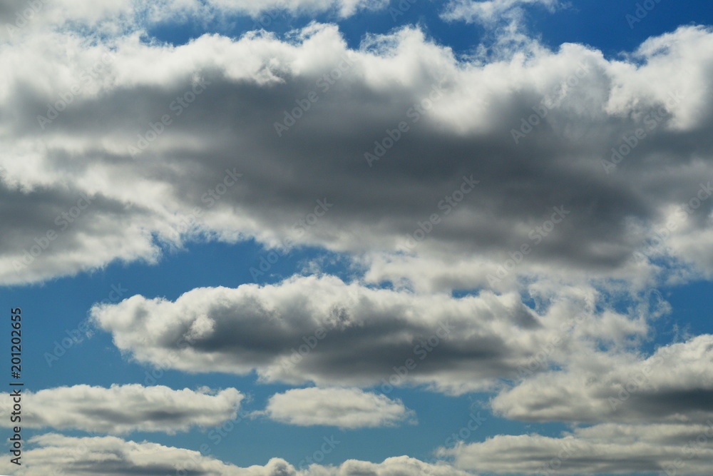 Small cumulus clouds are lit by the sun. The sun is not visible. Small cumulus clouds are lit by the sun. The sun is not visible.