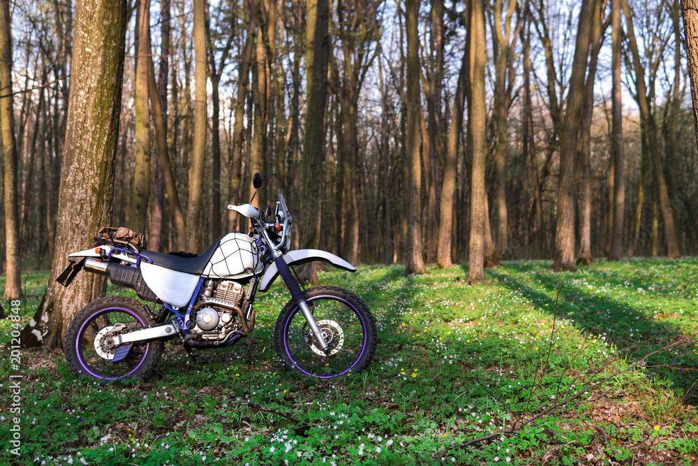 classic enduro motorcycle off road in spring forest, concept, active lifestyle
