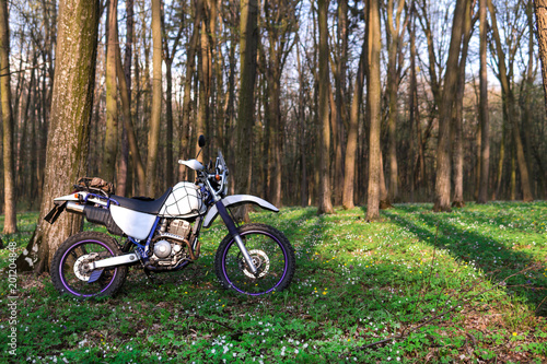 classic enduro motorcycle off road in spring forest, concept, active lifestyle