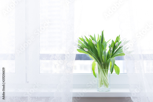 Bouquet of tulips in glass vase on windowsill