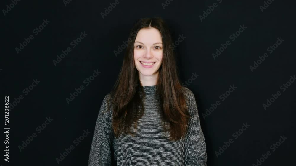 Young attractive brunette woman sends an air kiss to the camera and smiling in black background. Room for text. Young attractive brunette woman sends an air kiss to the camera and smiling in black background. Room for text.