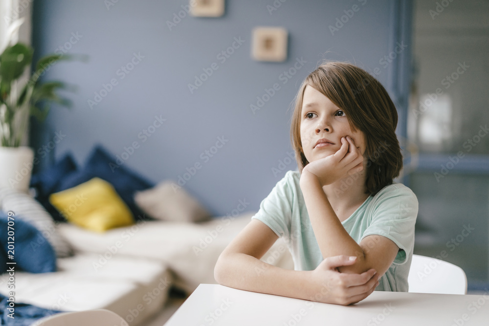 Portrait of sad boy sitting at table at home Portrait of sad boy sitting at table at home