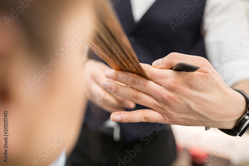 Hairdresser hands holding hair strand for cut