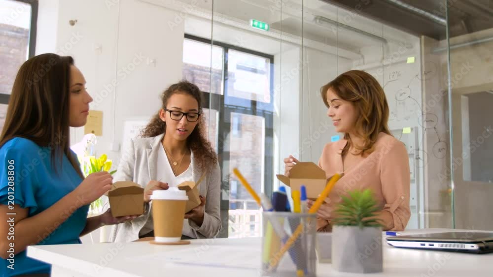 business lunch and people concept - happy businesswomen eating take out food at office business lunch and people concept - happy businesswomen eating take out food at office