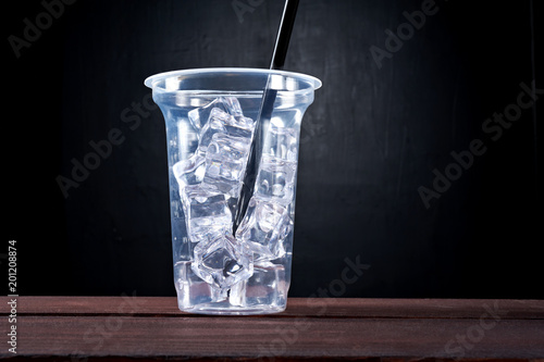 Plastic transparent cup of ice drink with straw isolated on black background. Drink - to go, take away, take out.