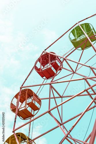 Ferris wheel in fun fair over vintage blue sky background for summer festival and amusement park holiday vacation theme park fiesta in old style concept 