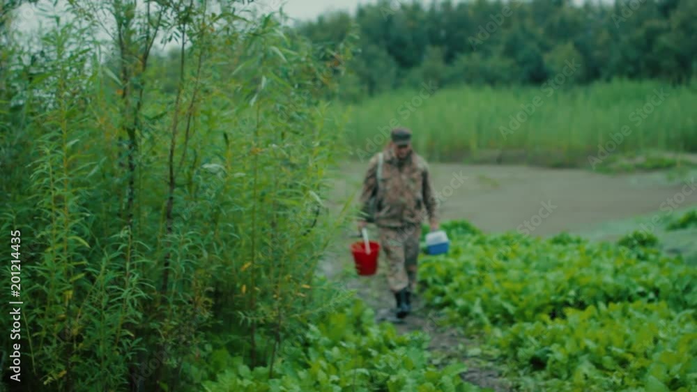 Fisherman on the road The fisherman came out from behind the bushes on the path leading to the bank of the river Fisherman on the road The fisherman came out from behind the bushes on the path leading to the bank of the river