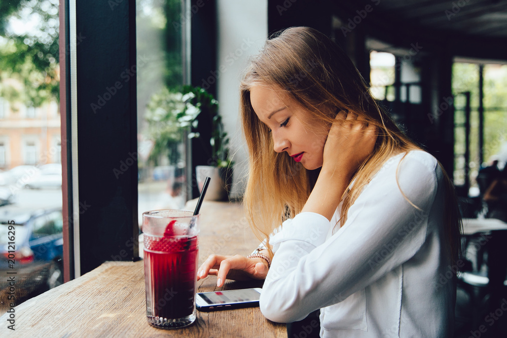 Profile of pretty woman, using a mobile phone, chatting, spending time with pleasure at cafe, drinking a fruit cocktail. Dressed in blouse. Profile of pretty woman, using a mobile phone, chatting, spending time with pleasure at cafe, drinking a fruit cocktail. Dressed in blouse.
