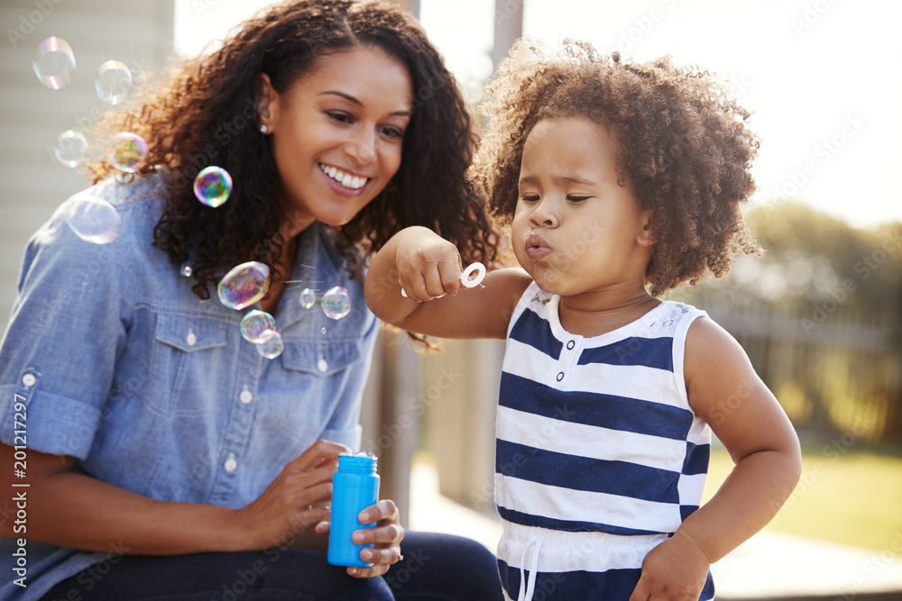 Young mixed race mother and daughter blowing bubbles outside Young mixed race mother and daughter blowing bubbles outside
