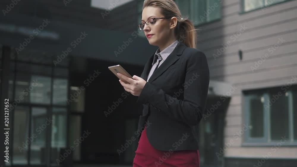 business woman walking down the street and sending a message from the smartphone. slow motion business woman walking down the street and sending a message from the smartphone. slow motion