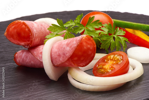 Tasty appetizer of thinly sliced spicy salami smoked sausage whith colorfull vegetabless on a stone rustic board isolated on white background photo