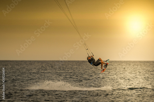 Kitesurfer jumping over the waves in Tenerife at the sunset. Kiter riding the waves on the ocean, enjoying the wind of a beautiful summer day.