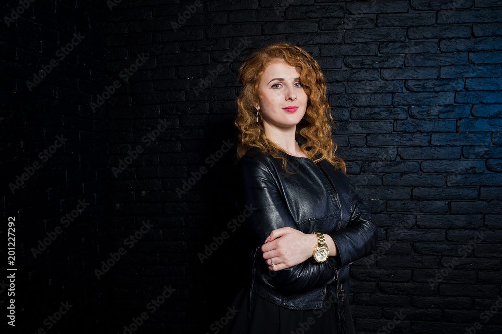 Curly hair girl at leather jacket on studio against black brick wall. Curly hair girl at leather jacket on studio against black brick wall.