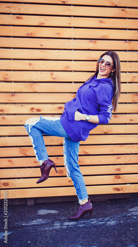 Fashion woman in sunglasses posing near wooden background. Summer time