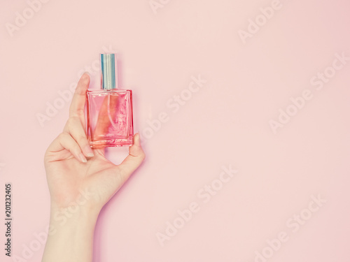 beauty for woman concept from beauty woman hand show and hold perfume bottle in hand with isolated pink pastel background
