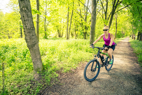 Woman cycling a mountain bike in city park, summer day © blas