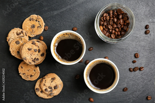 Flat lay composition with aromatic hot coffee in paper cups and cookies on dark background