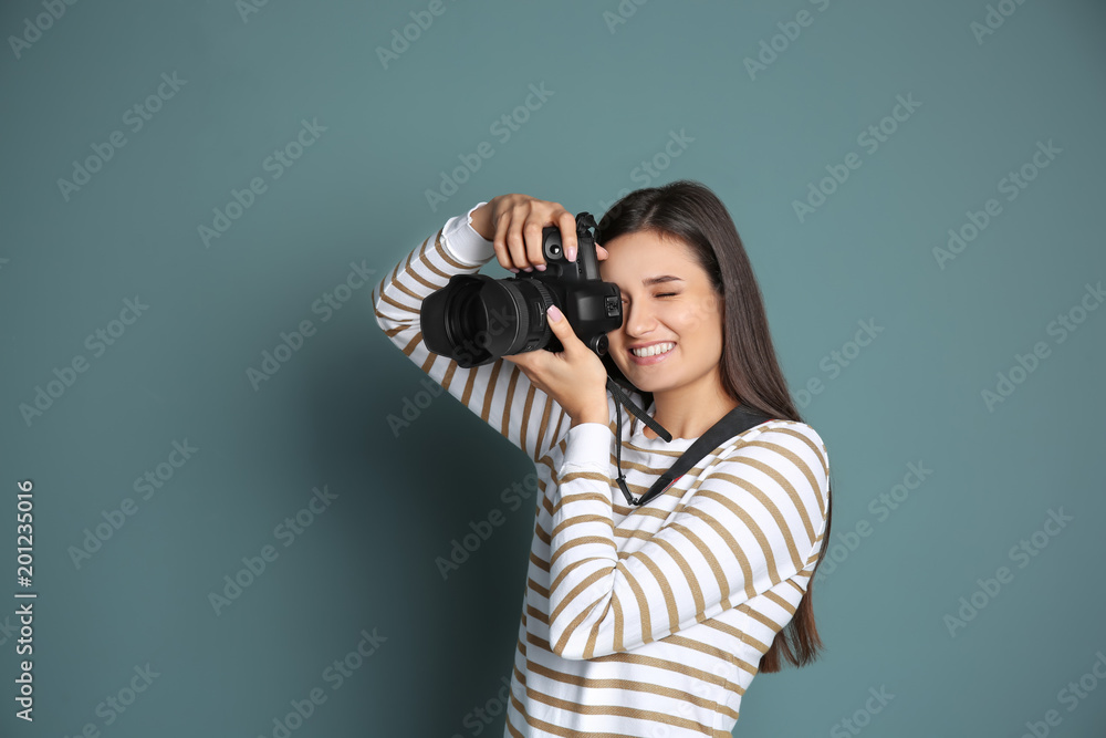 Young female photographer with camera on grey background Young female photographer with camera on grey background