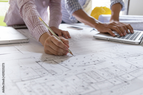 Two architects or engineers working on blueprint plans with a pencil in office. Team Architect or engineers working on architects project. working table.