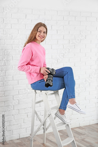 Female photographer with camera sitting on chair indoors