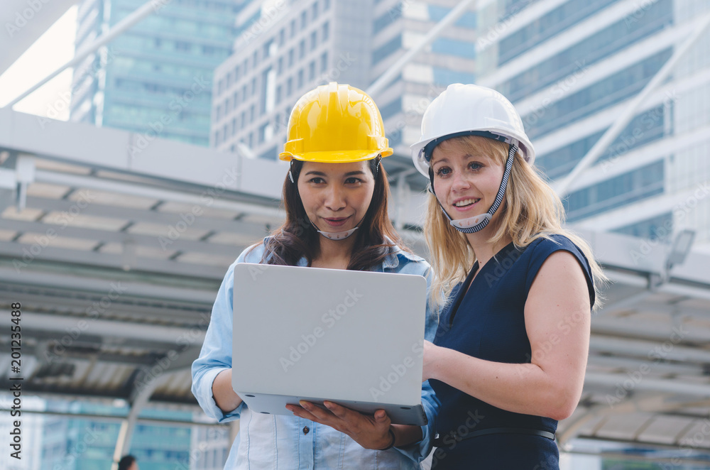attractive woman architecture and woman engineer together working at outdoor with laptop on working site. attractive woman architecture and woman engineer together working at outdoor with laptop on working site.