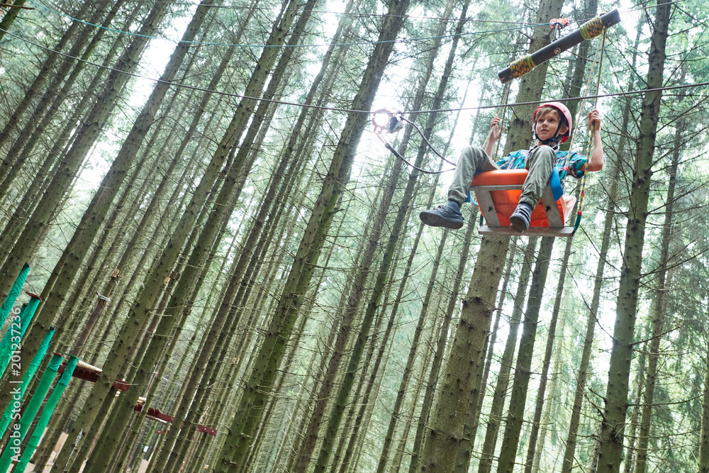 Fototapeta premium boy at climbing activity in high wire forest park