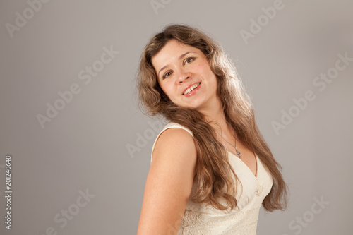 Fashion photo of a young charming woman with curly hair wearing white dress