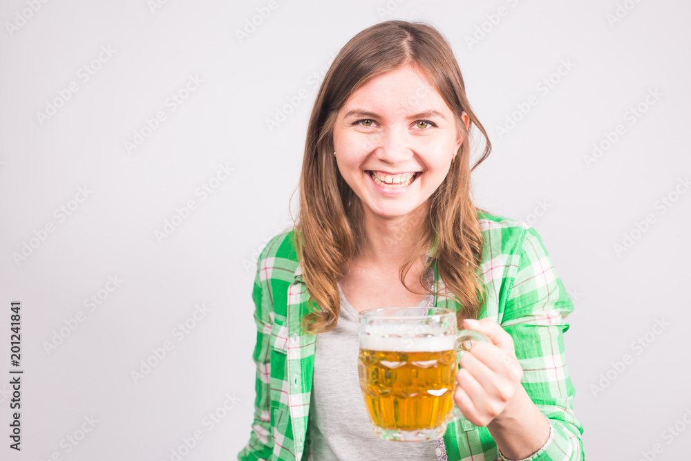 Cheerful young woman holding a beer mug full of beer and smiling on white background Cheerful young woman holding a beer mug full of beer and smiling on white background