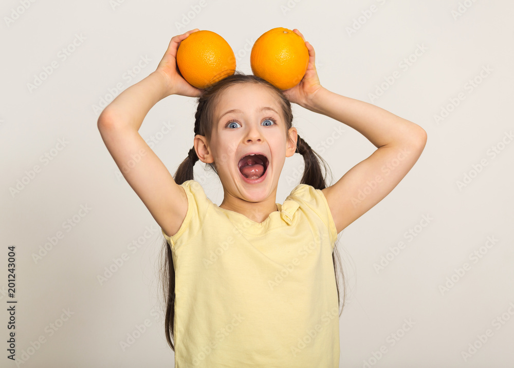 Happy little girl having fun with oranges over white background Happy little girl having fun with oranges over white background