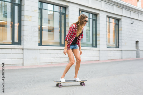 Beautiful young hipster woman with skateboard outdoors