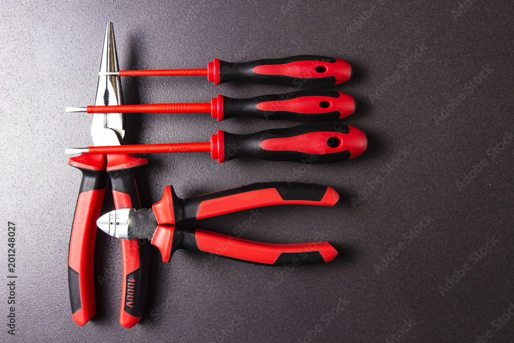 Tools electrician on a black background. Tool for working screwdriver, pliers, platypuses.