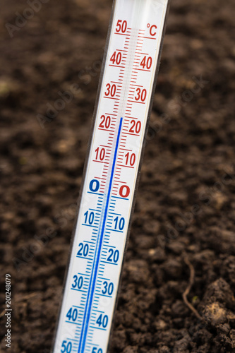 Thermometer for measuring soil temperature for gardening and planting plants against the background of the earth with a copy of the space