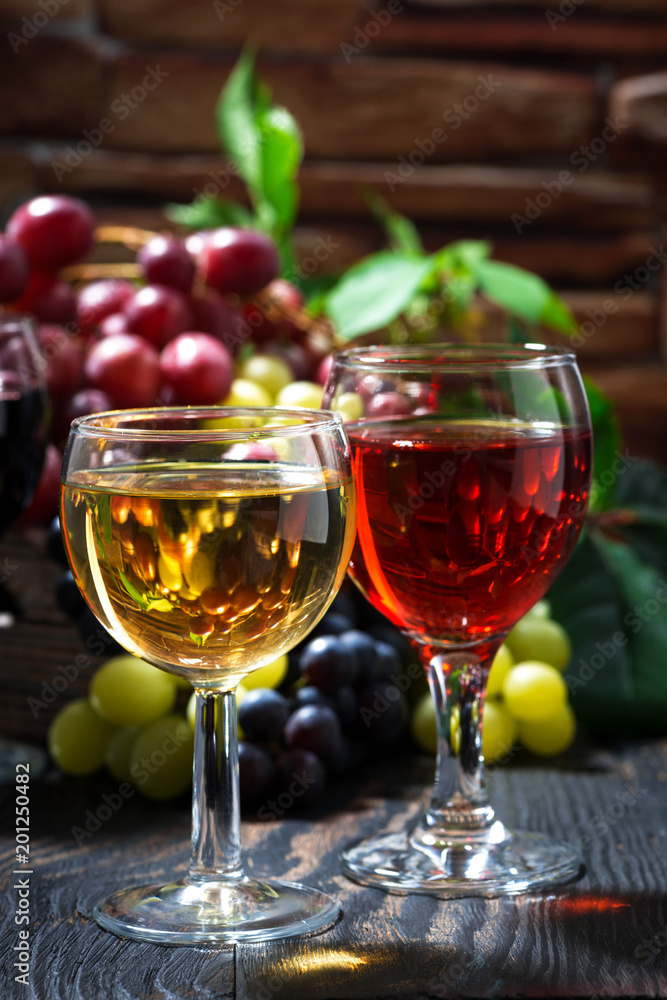 Fototapeta premium glasses of wine on dark wooden background, vertical