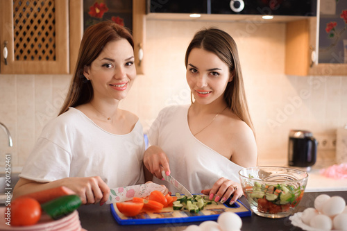 Smiling sisters preparing dinner together in the kitchen