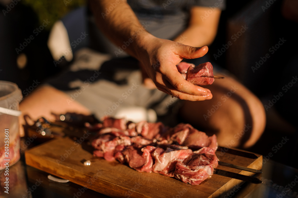 Man string a large fresh meat pieces on the skewer