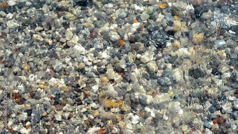 Waves washing the shore and transperent clear water move stones on the bottom. Top view Waves washing the shore and transperent clear water move stones on the bottom. Top view