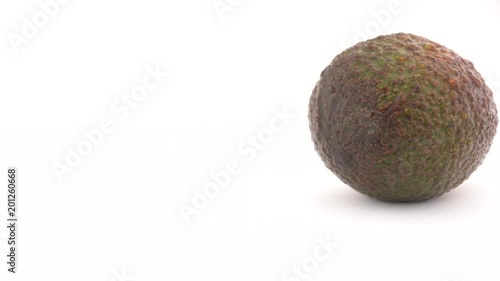 Camera is coming to slowly rotating avocado, isolated on white background. Close-up macro. photo